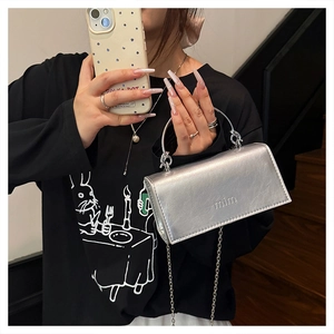 Détail du sac bandoulière argenté avec poignée ronde et logo MIM en relief