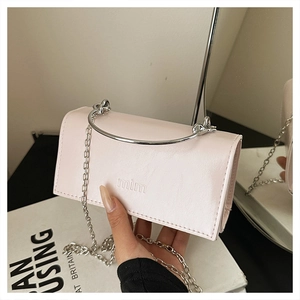 Détail d'un sac bandoulière en cuir rose avec poignée en métal argenté et logo mim