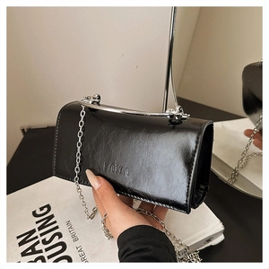 Détail d'un sac à main noir brillant avec poignée argentée et logo mim en relief