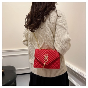 Detail of red quilted chain bag showing the V-pattern and gold S-lock on model