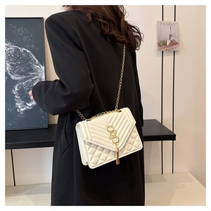 Detail of white quilted leather crossbody bag with gold chain and metal tassel