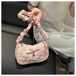 Detalle de bolso plisado rosa con bordado floral 3D y colgante de corazón de metal
