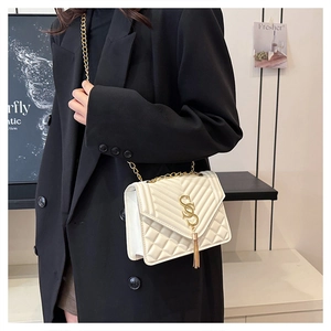 Close-up of beige quilted crossbody bag with golden S-buckle and elegant tassel detail