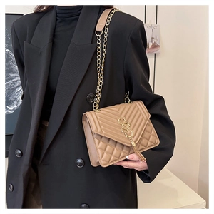 Detail of khaki quilted crossbody bag featuring a golden logo and long tassel pendant