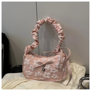 Detalle del bolso rosa tipo dumpling con texturas florales 3D y colgante de corazón