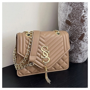 Detail of khaki quilted crossbody bag featuring a golden S-shaped buckle and metal fringe