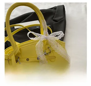Detail of yellow leather handbag with white lace bow and belt buckle adjustment