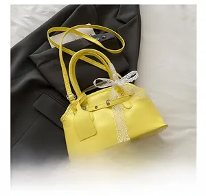 Detail of yellow shell bag with white lace bow and adjustable strap on black blazer