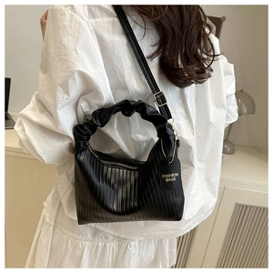 Detailed view of black pleated cloud bag worn by model over a white shirt