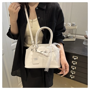 Détail du sac bandoulière carré blanc avec nœud en dentelle et étiquette logo