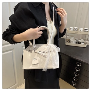 Detailed shot of a beige leather tote with a large lace bow and a branded hanging tag