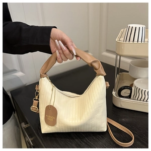 Detailed shot of pleated off-white handbag with brown scrunchie handle and logo tag