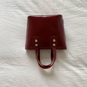 Detail view of burgundy PU leather bucket bag with decorative gold metal rivets