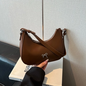 Brown faux leather hobo bag with a silver metal bow and adjustable shoulder strap