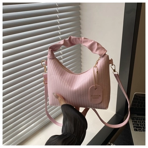Detail view of pink pleated cloud bag with vertical texture and gold metal hardware