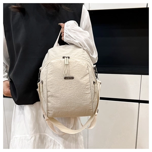 Detail of cream white pleated backpack with silver JING PIN metal logo and dual zippers