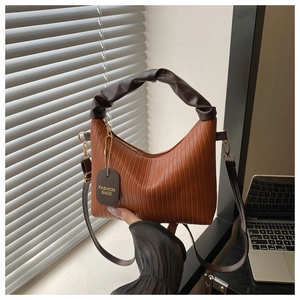 Detail of pleated texture handbag with gold chain strap and fashion bag charm