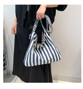 Detail of blue and white striped canvas tote featuring geometric wavy shoulder straps