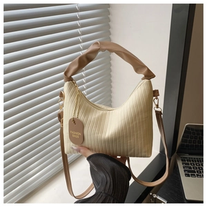 Detail of cream pleated fabric handbag with brown handles and gold logo chain tag