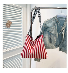 Detail of red and white striped canvas tote bag with woven geometric shoulder strap