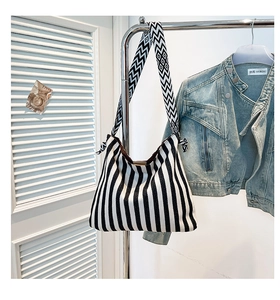 Detail of large black and white striped canvas tote with geometric woven shoulder strap