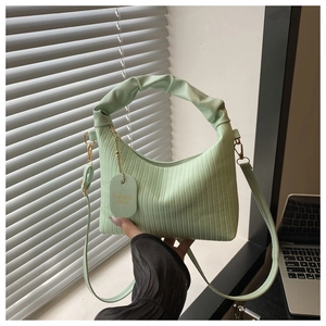 Detail of mint green pleated handbag with cloud handle and fashion bag tag accessory