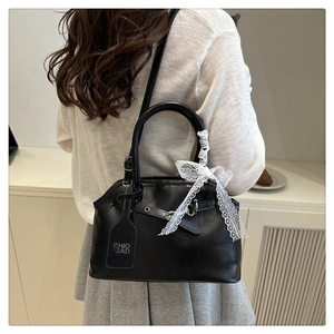 Fashionable black leather handbag featuring delicate white lace bow detail and shoulder strap