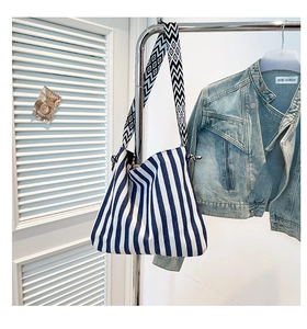 Detail of blue striped canvas tote bag with geometric woven shoulder strap and metal hardware