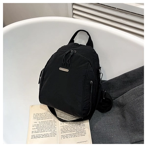 Close-up of black nylon backpack with metal logo plate on white background with books