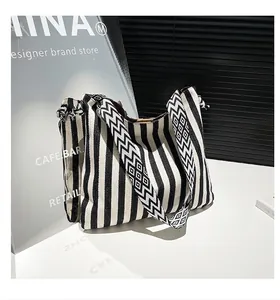 Detail of canvas tote bag showing striped texture and woven geometric shoulder strap