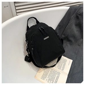 Detail of black nylon mini backpack featuring a metallic logo and adjustable strap