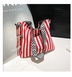 Detail of red striped canvas tote with a black and white geometric patterned wide strap