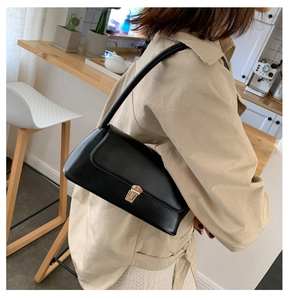 Sac baguette noir de style français avec boucle dorée, porté par un mannequin en trench-coat
