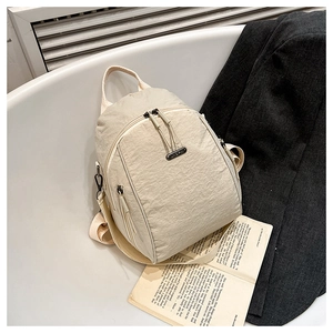 Detail of a beige nylon backpack with tassel zipper beside a suit and book