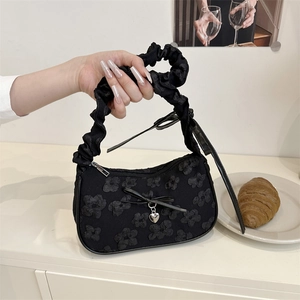 Bolso dumpling plisado negro con textura floral 3D y detalles de colgante de corazón