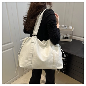 Detailed side view of white faux leather tote bag showing large capacity and strap texture