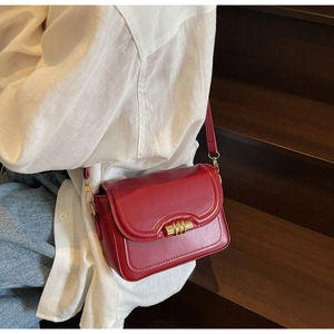 Detail of red PU leather crossbody bag featuring wave edge and gold cylinder lock
