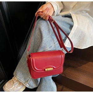 Chic red PU leather shoulder bag with gold metal lock held by a model in casual setting