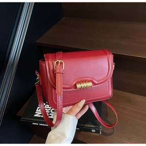 Close-up of red matte leather crossbody bag featuring a golden metal twist lock closure