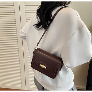Detail view of a vintage dark brown crossbody bag with a golden metal cylinder lock