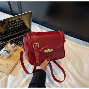 Detail of red PU leather crossbody bag with gold hardware in a modern lifestyle setting