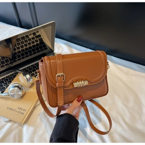 Close-up of brown faux leather crossbody bag featuring a golden twist-lock closure detail