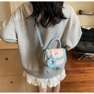 Detailed back view of a cute blue and beige crossbody bag with cherry prints and a donut charm