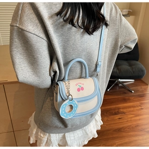 Detail of a mini saddle bag with cherry print, blue donut charm and AETOLO logo