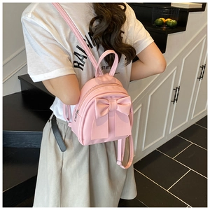 Detail of light pink mini backpack with a large bow decoration shown on model's back