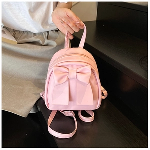 Detailed view of a pink mini backpack featuring a large decorative bow and PU leather texture