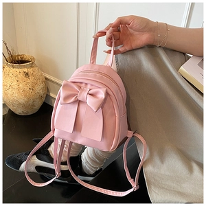 Close-up of pink mini backpack featuring a large bow and matte synthetic leather texture