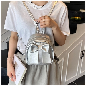 Detail of silver mini backpack with oversized bow and metallic finish for 2025 summer