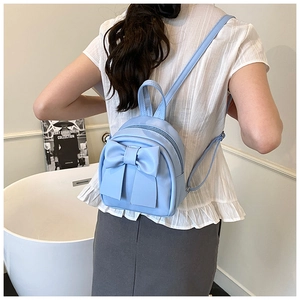 Close-up of light blue mini backpack featuring a large decorative bow and PU leather texture