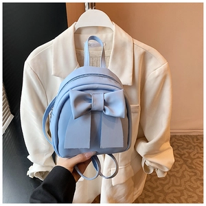 Detail of light blue mini backpack with large decorative bow and matte leather finish